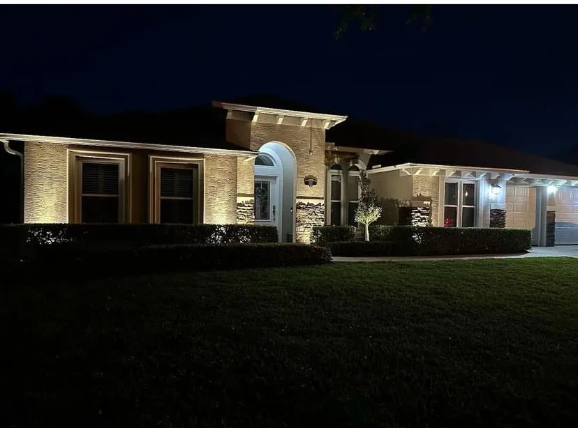 A well-lit home with a manicured lawn and colorful landscaping.